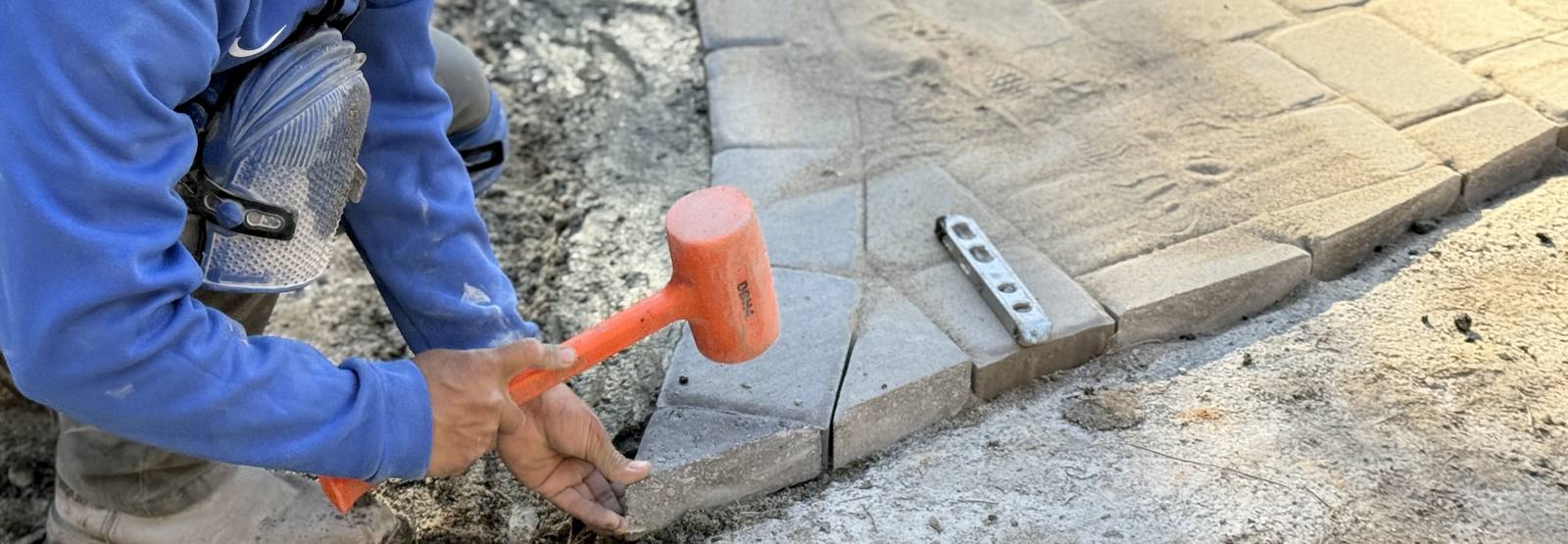 Worker using rubber mallet on pavers