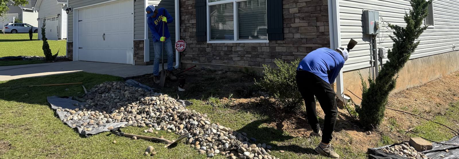 Team member placing landscape rocks near foundation