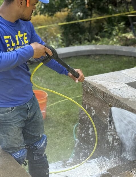 Team member applying lawn treatment with hose